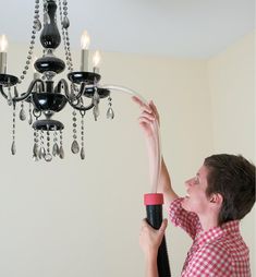 a woman is fixing a chandelier in her home