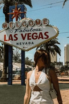 a woman is walking in front of the las vegas sign