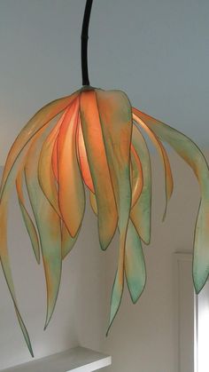 an orange and green flower hanging from a ceiling fixture in a room with white walls