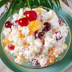 a bowl filled with fruit salad on top of a blue plate next to a palm leaf