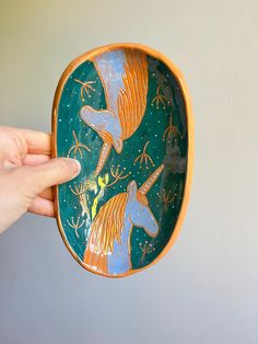 a hand holding a small decorative bowl with two birds on the side and stars in the sky