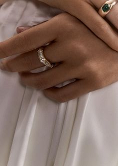 a close up of a person wearing two rings on their hands and holding another ring