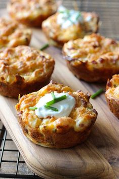 mini quiche cups with sour cream and chives on a wooden board next to a cooling rack