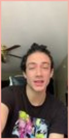 a man with his eyes closed sitting in front of a ceiling fan