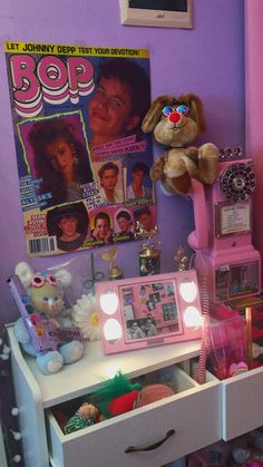 there is a stuffed animal on top of the dresser in this room with magazines and toys