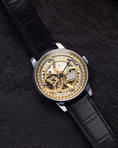 This customized Pobeda watch, with a 37 mm case, boasts a mesmerizing handcrafted skeleton dial that captures the beauty of celestial motifs. The intricate golden patterns etched into the dial evoke images of the cosmos, giving the timepiece an artistic and ethereal quality. The open-worked design of the dial not only enhances its aesthetic appeal but also provides a fascinating view of the inner mechanical workings, making it a true conversation piece. The watch's case is made from polished stainless steel, offering both durability and a sleek, modern look that contrasts beautifully with the ornate dial. This sturdy 37 mm case frames the celestial motif perfectly, ensuring that the dial remains the centerpiece of the design. Paired with a classic black leather strap, the watch exudes soph Gold Skeleton Dial Watch Accessories, Gold Watch Accessories With Skeleton Dial, Luxury Automatic Watch Accessories For Gift, Gold Round Skeleton Dial Watch, Gold Round Watch With Skeleton Dial, Luxury Automatic Watch As Gift, Steampunk Gold Watch As Gift, Steampunk Watch With Skeleton Dial, Gold Steampunk Watch For Gift