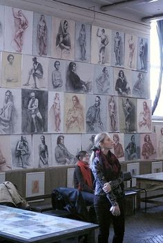 two people standing in front of a wall with drawings on it and one person looking up