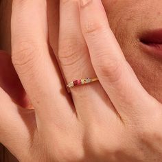 a woman's hand with a ring on her finger, holding it up to her face