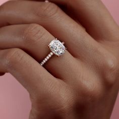 a woman's hand holding an engagement ring with a diamond on top and side stones