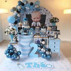 a table with balloons and decorations for a baby's first birthday party in blue and silver