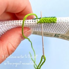 someone is knitting on the end of a piece of white fabric with green stitching