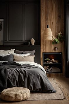 a bedroom with black walls and wood flooring has a large bed in front of a fireplace