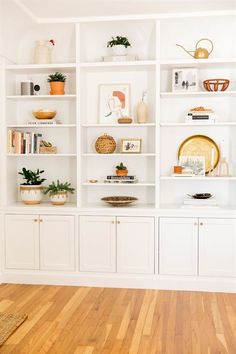 a living room with white bookcases filled with books and vases on top of them