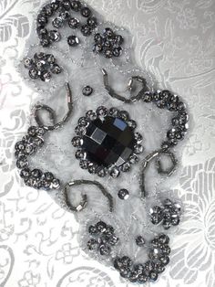 the brooch is made up of silver beads and black glass stones on white lace