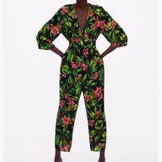 A Green Zara Jumpsuit With Pink Flowers Tropical Printed V-neck Jumpsuits And Rompers, Printed Tropical V-neck Jumpsuits And Rompers, Chic Tropical Print Jumpsuits And Rompers For Spring, Tropical V-neck Printed Jumpsuits And Rompers, Green Tropical V-neck Jumpsuits And Rompers, Pink Floral Print V-neck Jumpsuit, Pink Floral Print V-neck Jumpsuit/romper, Zara Green V-neck Jumpsuits And Rompers, Zara Fitted Jumpsuits And Rompers With Floral Print