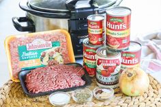 an assortment of canned meats and vegetables on a wicker basket next to the crock pot