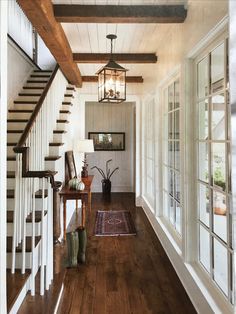 a hallway with wood floors, white walls and wooden railings that lead up to the second floor