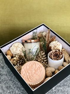 a box filled with pine cones, candles and other items on top of a table