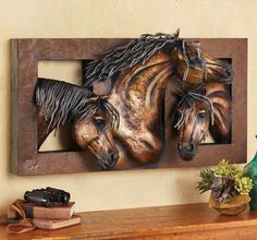 two horse heads mounted to the side of a wooden frame on a wall next to a potted plant