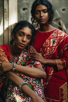 two women standing next to each other with their arms around one another and looking at the camera