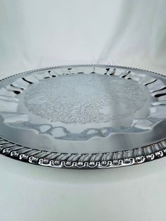 a silver plate with an ornate design on the bottom and sides, sitting on a white surface