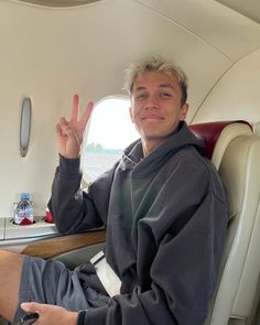 a man sitting in an airplane with his hand up