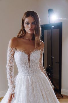 a woman wearing a wedding dress with long sleeves