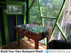 a foosball table in the corner of a room with green walls and windows