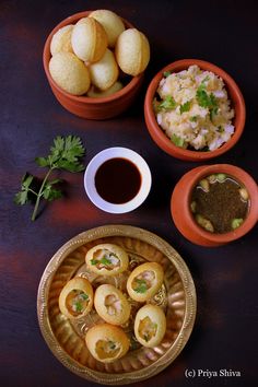 some food is sitting on a table next to two bowls with sauces and bread