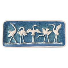 a blue and white tray with three birds on the bottom, one is holding an object in