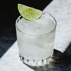 a glass filled with ice and a lime slice on top of it's rim