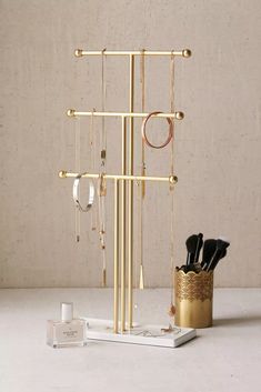 a gold jewelry rack with several pairs of earrings and rings hanging from it's sides