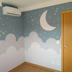 an empty room with painted clouds and stars on the wall next to a wooden door