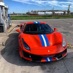 a red sports car parked at a gas station next to an electric vehicle charger