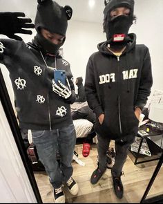 two people wearing black hoodies and masks