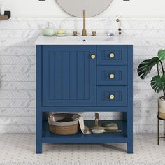 a bathroom vanity with blue drawers and a round mirror on the wall next to it