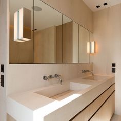 a bathroom with two sinks, mirrors and lights on the wall above them is shown