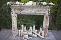 an old fireplace with candles and flowers on it