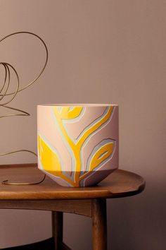 a coffee cup sitting on top of a wooden table next to a wire sculpture and lamp