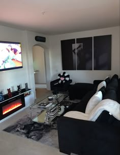 a living room with black and white furniture and a flat screen tv on the wall