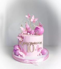 a pink and white cake with butterflies on it's top is decorated with the number ten