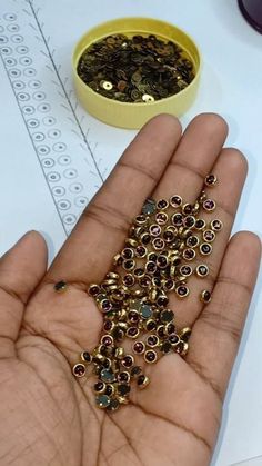 a person holding out their hand with some beads on it and a yellow bowl in the background