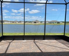 the view from inside an enclosed patio looking out onto a body of water with houses in the background