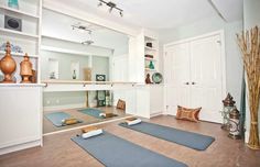 there are two yoga mats on the floor in front of an open door and some vases