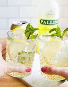 two glasses filled with lemonade and mint garnish on top of a tray