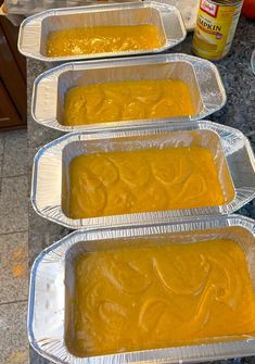 four pans filled with yellow food sitting on top of a counter next to an oven