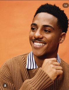 a young man is smiling and wearing a sweater