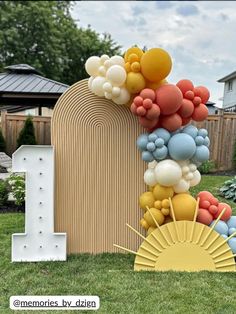 an outdoor display with balloons and decorations on the grass in front of a wooden fence