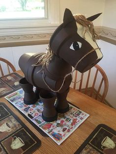 a paper mache horse sitting on top of a wooden table next to place mats