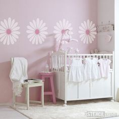 a baby's room decorated in pink and white with daisies on the wall